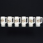 FAIANÇA, seis (6) canecas octogonais, ornamentações policromadas representando paisagens com charretes puxadas por duas parelhas de cavalos, arremates a ouro, ínfimas falhas na douração, sem marca de manufatura aparente, medindo 14,5 cm altura, sinais de uso, vide foto.