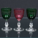 VIDRO, três (3) taças para licor, translúcidas, bojo nas tonalidades verde (2) e vermelha (1), fuste no formato de balaustre e base em bolacha, ambos incolores, bojo com lapidação contínua, manufatura FRATELLI VITA (fábrica de cristais fundada em 1902, pelos irmãos Giuseppe Vita e Francesco Vita, na cidade de Salvador na Bahia, no início como fábrica de licores, vinhos e refrigerantes, mais tarde com as dificuldades em importar as garrafas devido a Primeira Grande Guerra Mundial, passou a fabricar os próprios engradados, a partir de 1920 aventurou-se na produção de cristais recebendo diversas premiações em exposições internacionais, na década de 50 no apogeu da fabrica, financiou o trio elétrico de Dodô e Osmar em 1951 e a candidatura de Martha Rocha para Miss Brasil em 1954, que virou garota propaganda da fabrica, com a transferência da capital do Brasil do Rio de janeiro para Brasília, a Primeira Dama Sara Kubitschek, encomendou um jogo de taças com o Brasão da república impresso a ouro, a fabrica fechou em 1962), medindo 10 cm altura, ideais para coleção de cristaleira, sinais de uso, vide foto.