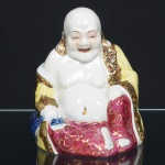 LOUÇA, uma (1) escultura representando Deus HOTEI (um dos 7 Deuses da Boa Sorte, Fortuna e Felicidade, integrantes do Shichi Fukujin, segundo o Xintoísmo, Mitologia e Folclore Japonês é o deus da felicidade e prosperidade), pintado a mão em policromia, arremates a ouro, boca aberta, orelhas furadas, manufatura SANTA TEREZINHA (Pedreira, SP, criada em 1949 e legalizada em 1952 por Luis Broglio, Pedro Chiarotti, Paschoal Ferraresso e Hamilton Valente; em 1960 também começou a produzir isoladores de porcelana; em 1977 encerrou a produção de louça domestica para se dedicar somente a isoladores, ainda em atividade), medindo 19 cm altura, sinais de uso, vide foto.