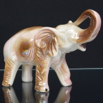 ESCULTURA, uma (1) representando elefante, confeccionada em louça, ornamentação policromada pintada a mão e perolizada, sem marca de manufatura aparente, medindo 19 cm comprimento, vide foto.