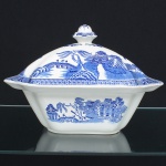 FAIANÇA INGLESA, uma (1) sopeira com tampa, quadrangular, ornamentação dita WILLON (Segundo a lenda chinesa: Um certo Mandarim tinha uma leal e devotada filha, possuidora de rara beleza. Certo dia, em que descobre que ela estava apaixonada por um carteiro que lhe fazia a corte, e que era por ela correspondida, expulsa a filha de casa e roga-lhe uma praga: que ao ser trocado o primeiro beijo pelo casal, eles se transformariam em dois pombos), também conhecida como pombinhos, manufatura WOOD & SONS Ltd. (fundada em 1865, funcionou na Potteries New Wharf em Trent e mais tarde na Pottery Stanley em Burlem, fechou em 2005), tonalidade azul sobre fundo branco, medindo 27 x 27 x 19 cm, possui o craquelê característico do envelhecimento de toda a faiança, sinais de uso, vide foto.