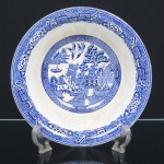 FAIANÇA INGLESA, uma (1) saladeira tipo bowl, ornamentação dita WILLON (Segundo a lenda chinesa: Um certo Mandarim tinha uma leal e devotada filha, possuidora de rara beleza. Certo dia, em que descobre que ela estava apaixonada por um carteiro que lhe fazia a corte, e que era por ela correspondida, expulsa a filha de casa e roga-lhe uma praga: que ao ser trocado o primeiro beijo pelo casal, eles se transformariam em dois pombos), também conhecida como pombinhos, manufatura WOOD & SONS Ltd. (fundada em 1865, funcionou na Potteries New Wharf em Trent e mais tarde na Pottery Stanley em Burlem, fechou em 2005), tonalidade azul sobre fundo branco, medindo 23,5 cm diâmetro, trincado na borda, possui o craquelê característico do envelhecimento de toda a faiança, sinais de uso, vide foto.