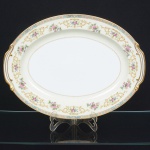 PORCELANA JAPONESA, uma (1) travessa oval, ornamentação floral policromada, borda com faixa na tonalidade azul claro e elementos vegetalistas em policromia, arremates a ouro, manufatura NORITAKE (1858 - Japão assinou o Tratado de Amizade e Comércio com os EUA, Holanda, Rússia, Reino Unido e França; 1867 fim do Shogunato e início da era Meiji; 1876 - Morimura-Kumi formada em Tóquio para exportação Os Morimuras & The Okuras unidos, a Companhia Hinode se estabelece na cidade de Nova York para o varejo; 1879 - A Companhia Hinode fecha. Morimura Bros & Co., se estabelece em Nova York; 1880 - Hiroses juntou-se a Morimura-Kumi em Tóquio; 1882 - Morimura Bros & Co., decidiu ser o atacadista; 1884 Morimura-Kumi subcontrata atelieres de decoração em porcelana nas cidades de Tokyo, Nagoya e Kyoto; 1918 - Morimura-Kumi é reorganizada como Morimura Bros, Inc.; 1921 - Morimura Bros de New York é incorporada a Morimura Bros, Inc. De Tokyo; 1947 - Noritake Co., Inc. com sede em Nova York; 1981 - Nome japonês da Companhia alterado para Noritake Co. Limited), modelo COLBY, medindo 42 x 31 cm, sinais de uso, vide foto.