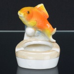 LOUÇA, um (1) antigo cinzeiro policromado, encimado por escultura representando peixe, arremates com frisos a ouro, sem marca de manufatura aparente, medindo 11 cm altura, sinais de uso, vide foto.