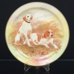 PORCELANA, um (1) prato decorativo policromado representando cachorros, manufatura ROYAL DOULTON (fundada em 1815 como JONES, WATTS & DOULTON parceria entre John Doulton, Martha Jones e John Watts em Vauxhall Walk, Lambert, Londres; em 1820 virou DOULTON & WATTS com a saída de Martha Jones; em 1854 virou DOULTON & Co. com a aposentadoria de John Watts e a fusão com a HENRY DOULTON & Co.; em 1902 virou ROYAL DOULTON através de concessão real; em 2009 passou a ser administrada pela Holding WWRD Waterford Crystal, Wedgwood, Royal Doulton; em 2015 foi adquirida pela empresa finlandesa FISKARS CORPORATION), medindo 26,5 cm diâmetro, sinais de uso, vide foto.