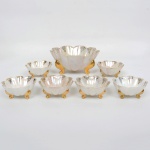 PORCELANA, conjunto para sobremesa com sete (7) itens: 1 saladeira e 6 taças, modelagem em gomos, pés terminando em volutas, fundo nacarado, generosos arremates a ouro, manufatura CSA (SANTANA, Pedreira, SP, fundada em 1941 por Joaquim Carlos e Flamínio Maurício Netto; em 1943 entraram os sócios Adelino dos Santos Gouveia e Horácio Lopes; em 1966 comprou do grupo Nadir Figueiredo as instalações da antiga Santa Rita, onde fundou a Porcelana Veracruz, que passou a produzir louça doméstica e a Santana passou a produzir apenas isoladores elétricos; em 2000 ocorre a integração de ambas e passam a produzir somente isoladores), medindo respectivamente 20 cm diâmetro e 9,5 cm altura; 10,5 cm diâmetro e 5 cm altura, sinais de uso, vide foto.