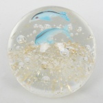 VIDRO, um (1) peso de papel, incolor e translúcido, sulfitos internos coloridos representando peixes, mossa na base, medindo 6 cm altura, vide foto.