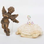 DIVERSOS, dois (2) itens distintos: 1 anjo musicista para ornar parede, confeccionado em resina, tonalidade bronze, medindo 13 cm altura; 1 boneca de porcelana de meio corpo, policromada, base em saia rodada em tecido, acabamentos em renda, medindo 9 cm altura, sinais de uso, vide foto.