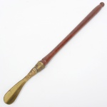 DIVERSOS, uma (1) calçadeira confeccionada em bronze, cabo em madeira torneada, medindo 64 cm comprimento, sinais de uso, vide foto.