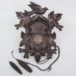 RELÓGIO, um (1) carrilhão de parede, dito cuco, gabinete entalhado em madeira, em elementos vegetalistas encimado por pássaro, mostrador em metal com algarismos romanos, possui os pêndulos, medindo 39 cm altura, usado, não testado e sem garantia, vide foto.