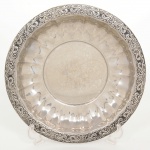 AÇO INOX, uma (1) fruteira circular com bojo plissado, borda relevada em volutas e elementos vegetalistas, selo da manufatura MERIDIONAL, medindo 30,5 cm diâmetro e 4 cm altura, sinais de uso, vide foto.