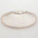 METAL PRATEADO, um (1) covilhete no formato de concha bivalve, manufatura WOLFF (tradição desde 1894), selo das lojas RACHEL, medindo 29 x 18,5 cm, sinais de uso, vide foto.