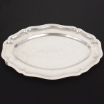 AÇO INOX, uma (1) travessa oval, borda plissada e recortada, sem marca de manufatura aparente, medindo 45,5 x 29,5 cm, sinais de uso, vide foto.