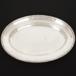 METAL PRATEADO, uma (1) travessa oval, borda reforçada e relevada no padrão Império Napoleônico com frisos intercalados por X, manufatura WOLFF (tradição desde 1894), medindo 37 x 25 cm, sinais de uso, vide foto.