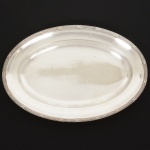 METAL PRATEADO, uma (1) travessa oval, borda reforçada e relevada no padrão Império Napoleônico com frisos intercalados por X, manufatura WOLFF (tradição desde 1894), medindo 37 x 25 cm, sinais de uso, vide foto.