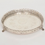 METAL PRATEADO, uma (1) salva circular, ornamentação do fundo burilado em flores, acabamentos executados com carretilhas, borda vazada em elementos vegetalistas, pés com terminações em garras e elementos vegetalistas, sem punções aparentes, medindo 21 cm diâmetro, sinais de uso, vide foto.