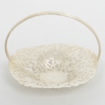 METAL PRATEADO, uma (1) pequena fruteira com alça, formato de cesta, vazada em elementos vegetalistas, manufatura MERIDIONAL, medindo 12 x 8 cm, sinais de uso, vide foto.