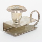 METAL PRATEADO, uma (1) palmatória fosforeira, lisa, alça em meia cana vergada, pés em meia esfera, medindo 8,5 cm comprimento, sinais de uso, vide foto.