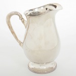 METAL PRATEADO, uma (1) jarra refresqueira, formato de balaustre, possui retentor de gelo, alça com terminações em volutas, pé baixo, manufatura BELPRATA, medindo 21 cm altura, sinais de uso, vide foto.