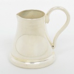 METAL PRATEADO, uma (1) cremeira miniatura, ligeiramente cônica, frisos horizontais, alça sinuosa, marca REVEILLON, padrão Inglês Georgiano, medindo 5,5 cm altura, sinais de uso, vide foto.