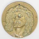 ARTE SACRA, uma (1) placa uniface, representando cabeça de Cristo, possui furo para fixação na parte superior, medindo 10,5 cm diâmetro, sinais de uso, vide foto.
