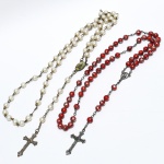 ARTE SACRA, dois (2) antigos terços distintos: 1 com contas em polímero, pintadas na tonalidade vermelha com mesclados prateados, cruz e monture em metal, medindo 44 cm; 1 com contas imitando madrepérola, cruz e monture em metal medindo 57 cm, ambos com sinais de uso, vide foto.