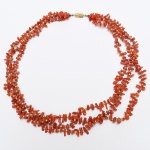 JOIA, uma (1) gargantilha de três voltas, confeccionada com contas em coral intercaladas por contas esféricas douradas, monture em metal, fecho rosqueável, medindo a maior volta 46 cm comprimento, sinais de uso, vide foto.