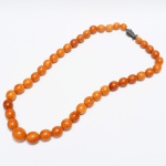 JOIA ORIENTAL, um (1) colar com contas em âmbar, dita cera de abelha, dispostas em degrade, medindo 60 cm comprimento, fecho em PRATA, punção não identificado, sinais de uso, vide foto.