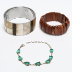 BIJUTERIAS, três (3) itens dentre braceletes e pulseira: 1 em metal prateado com apliques em placas de madrepérola, medindo 7 cm diâmetro e 3,5 cm largura; 1 elástica com barretes em pedra do sol (feldspato aventurino), dois deles quebrados, medindo2,5 cm largura; 1 em metal prateado com pedras ou vidro verde, lapidação gota, monture em metal prateado, fecho do tipo lobster, medindo 20 cm comprimento, todos os itens com sinais de uso, vide foto.