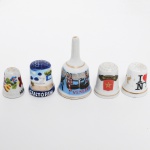 COLECIONISMO, cinco (5) itens: 4 dedais e 1 sineta, confeccionados em porcelana e faiança, todos souvenires de regiões diversas: New York; Marrocos; Santorini; Hungria e Veneza, medindo a maior peça 5,5 cm altura, vide foto.