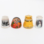 COLECIONISMO, quatro (4) dedais distintos: 1 em porcelana, marca REUTTER, ornamentação policromada representando retrato perfilado feminino; 1 em resina, propaganda de TAXI de New York; 1 em porcelana com ornamentação floral policromada, cão e legenda; 1 em cerâmica policromada e figurativa, medindo o maior 3,5 cm altura, vide foto.