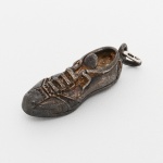 JOIA, um (1) pingente no formato de chuteira, confeccionado em PRATA, contrastado 925 milésimos, medindo 4 cm mais olhal e argola, peso 14,1 gr., sinais de uso, vide foto.