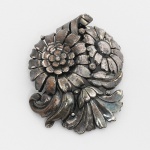 BIJUTERIA, um (1) antigo broche representando flores, confeccionado em metal prateado, marca TRIFARI (tradição desde 1889 em New York, USA), medindo 5,5 x 4,5 cm, sinais de uso, vide foto.