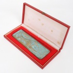 Placa de bronze dourado, contendo composição de motivo surrealista em relevo, representando figura antropormórfica. Verso assinado HALLES, datada de Dezmbro 1972. Acondicionado em estojo. Medidas: 10 x 6 cm.