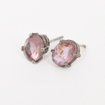 Joia. Prata. Par de brincos confeccionados em prata, compostos por engastes ovais com galerias vazadas. Cada exemplar apresenta gema lapidada em formato oval facetado, cravada em quatro garras, gemas em tonalidade rosa a lilás, possivelmente quartzo, variedade rosada ou ametista clara. Sistema de uso por pino e haste posterior para orelha perfurada. Sem tarraxas. Estado conforme fotografias. Medidas: Alt.: 0.9 x Comp.: 0.6 cm. Comp.: 1,8 cm. Peso total: