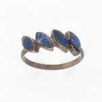 Anel confeccionado em prata, composto por aro circular e parte superior formada por quatro elementos em sequência, com engastes individuais. Cada elemento apresenta pedra azul de formato irregular, lapidação cabochão, inserida em engaste fechado. Medida: Peso: 2 gramas.