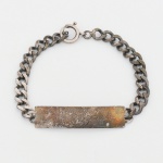 JOIA. PRATA. Pulseira com placa central em prata, composta por corrente de elos ovais interligados, unida a placa central retangular, destinada à gravação de marca possessória.Fecho tipo bóia. Apresenta marca possessória. Medida aberta: 20 cm. Peso: 16,4 gramas.