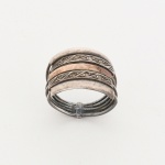 JOIA. PRATA E OURO. Anel confeccionado em prata, composto por cinco aros paralelos interligados por travessa central retangular. Dois aros externos lisos e abaulados. Dois aros intermediários com friso gravado em padrão geométrico, apresentando pequenas marcassitas cravadas em assentos circulares. Aro central em ouro liso e abaulado. Estrutura posterior unida por elemento tubular transversal. Medida: 2 cm. Peso: 4,9 cm.