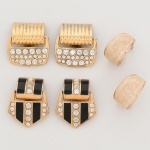 BIJUTERIA. Três(03) itens: a) Brincos em metal dourado, estrutura composta por elemento superior semicilíndrico com frisos paralelos em relevo, articulado a placa inferior levemente trapezoidal, pavimentada com pedras sintéticas incolores lapidadas em formato redondo, cravadas em engastes perfurados. Sistema de fecho tipo pressão (clip). b) Brincos em metal dourado, composição articulada em dois corpos: elemento superior curvo com aplicação central de pedras sintéticas incolores dispostas em fileira vertical; elemento inferior geométrico com painéis em esmalte preto intercalados por fileira central de pedras sintéticas incolores. Verso com base texturizada e sistema de fecho tipo pressão (clip). c) Par de brincos em metal dourado, modelagem tipo meia-argola de seção larga e perfil convexo, decorado com aplicação sintética em tonalidade marfim, superfície texturizada com padrão orgânico. estrutura interna metálica com bordas polidas aparentes. Sistema de fixação por pino e tarraxa.