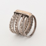 JOIA. PRATA E OURO. Anel confeccionado em prata, constituído por múltiplos aros paralelos, alternando seções lisas e torcidas (fio retorcido helicoidal), formando estrutura vazada e escalonada na parte frontal, aros unidos por elemento vertical retangular central, superfície em ouro amarelo, texturizada por pontilhado (acabamento martelado/estampado). Estado conforme fotografia. Medidas: Diam.: 2 cm; Comp.: 1,7 cm. Peso: 8,9 cm.