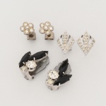 BIJUTERIA. Três(03) itens: a) Par de brincos em metal prateado, com composição geométrica vertical. Cada exemplar apresenta três pedras de formato navete, em tonalidade escura, lapidação facetada, cravadas por garras. Associam-se duas pedras circulares facetadas, incolores a levemente amareladas, igualmente fixadas por garras; gemas montadas sobre base metálica recortada, com estrutura posterior dotada de fecho de pressão tipo garra (clip), em chapa metálica articulada com mola. Medidas: Alt.: 2,5 x Comp.: 1,5 cm; b) Par de brincos em metal prateado, compostos por elemento frontal em formato floral. Cada exemplar apresenta seis pedras circulares facetadas, de tonalidade incolor a levemente amarelada, dispostas com uma pedra central circundada por cinco periféricas, cravadas em chatões circulares com bordo elevado. Montagem posterior com pino reto e tarraxa tipo borboleta (fecho de fricção). Medidas: Comp.: 1,5 cm; c) Par de brincos em metal prateado, de formato losangular, com composição frontal vazada. Cada exemplar apresenta elemento central em forma de navete estilizada, circundado por moldura perimetral com microesferas decorativas (bordo perlado), superfície pavimentada por múltiplas pedras circulares facetadas, de tonalidade incolor a levemente amarelada, fixadas por cravação em grãos e garras. Estrutura posterior com pino reto soldado à base e fecho tipo borboleta (tarraxa de fricção). Medidas: Alt.: 1,8 x Comp.: 1,2 cm. Estado de conservação conforme fotografias. 