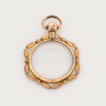 Pingente de formato circular, confeccionado em metal com acabamento dourado.Estrutura composta por moldura externa em motivo de corrente estilizada, envolvendo caixa circular com acrílico translúcido, próprio para acondicionamento de retrato, relicário ou miniatura. Parte superior com argola fixa rosqueável, composta por esfera terminal com rosca interna, permitindo a abertura do conjunto. Peça desmontável, com compartimento interno destinado à inserção de elemento decorativo ou devocional. Medida: Diam.: 3 cm.