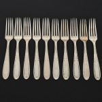 RADIO ALPACA. Conjunto de garfos para sobremesa confeccionadas em alpaca espessurado à prata, cabo de ponta oval, ricamente relevado com folhas de acanto e borda contornada por fileira perlada. Marca da manufatura puncionada no verso. Composto de dez(10) unidades. Apresentam marcas de uso e do tempo, vide foto. Medida: Comp.: 17 cm.