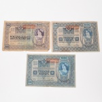 Três(03) cédulas  Coroas austríacas. Conjunto composto por três cédulas estrangeiras do Império Austro-Húngaro / República da Áustria, pertencentes ao período de transição monetária após a Primeira Guerra Mundial. a) Cédulas de 1000 Kronen (Mil Coroas)  duas unidades. Emitidas pelo OesterreichischUngarische Bank, com inscrições em língua alemã e composição ornamental guilhochê. Anverso com brasão imperial austro-húngaro e valor Tausend Kronen, acompanhado de carimbo vermelho com a inscrição Deutschösterreich, aplicado após a dissolução do Império em 1918 para validar as notas no território da nova República da Áustria. Reverso com composição decorativa apresentando medalhões com busto feminino alegórico, representando a personificação feminina do Estado austríaco, e arabescos ornamentais; b) Cédula de 10.000 Kronen (Dez Mil Coroas)  uma unidade. Emitida pelo Oesterreichische Nationalbank, já no período da República da Áustria. Anverso com legenda Zehntausend Kronen e composição ornamental semelhante às emissões anteriores, acompanhada de carimbo territorial. Reverso com medalhões femininos alegóricos e ornamentação simétrica em estilo guilhochê. As peças pertencem ao sistema monetário baseado na coroa austro-húngara (Krone/Krone), vigente entre o final do século XIX e as primeiras décadas do século XX, período marcado por sucessivas emissões e revalidações decorrentes da fragmentação do Império Austro-Húngaro após 1918. Apresentam rasgos e dobraduras, estado conforme fotografias.