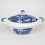 Johnson Brothers, Staffordshire - Inglaterra(Fundada em 1883). Belíssima sopeira executada em faiança inglesa, padrão Watermill. Decoração monocromática em azul sob esmalte, representando paisagem rural com moinho hidráulico, executada por estampagem. A composição mostra edifício de moinho com roda dágua em funcionamento, pequeno dique e queda d'água, acompanhados por casas campestres, árvores frondosas, figuras humanas em ambiente bucólico e céu anuviado ao fundo; bojo de formato hemisférico, abas laterais integradas, orla e tampa modeladas com delicado movimento ondulado, borda recortada com arcos em repetição, puxador em forma de domo. Marca da manufatura no verso. Medidas: Alt.:  16 x Diam.: 29 cm. Apresenta leves manchas do tempo na parte interna.