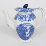 Wood & Sons, Burslem - Inglaterra(Fundada em 1865). Bule para café em faiança inglesa do início do século XX, c1918; esmaltada com decoração em azul sob o vidrado, corpo bojudo apoiado sobre pé circular, provido de bico vertedor alongado e alça posterior em arco. Boca larga com borda ligeiramente ondulada, acompanhada de tampa removível com pega superior modelada com feitio de fruto; superfície externa apresenta decoração monocromática em azul cobalto sob vidrado, composta por paisagem campestre com construção rural, árvores frondosas e curso d'água, enquadrada por faixa superior de motivos florais e folhagens estilizadas. Elementos florais adicionais decoram o bico vertedor. Marca de fábrica na base com inscrição ENOCH WOODS  ENGLISH SCENERY  WOODS WARE  WOOD & SONS  ENGLAND. Medidas: Alt.: 18 x Comp.: 20 x Larg.: 11 cm. Apresenta pequena quebradura na ponta do bico vertedor.