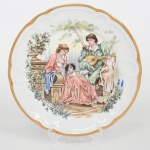 Prato de coleção em porcelana francesa, manufatura de Limoges, borda recortada em contorno ondulado e aba larga. Decoração policroma em esmaltes sobre vidrado, com filete dourado contínuo na orla. Campo central com cena galante em policromia, representando casal em ambiente ajardinado, com figura feminina sentada ao lado de cão de colo e figura masculina tocando instrumento de cordas. Elementos arquitetônicos e vegetação ao fundo. Verso com marca em azul sob esmalte com inscrição Limoges  Décoration à la main. Medida: Diam.: