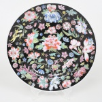 Belíssimo prato em porcelana chinesa, decoração botânica em esmalte policromado e relevado, distribuído sobre fundo de tonalidade preta. Marca da manufatura e inscrição "MADE IN CHINA" no verso. Medida: Diam.: 23 cm.