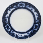 Fábrica de Loiça de Sacavém (Gilman & C.ª), Sacavém, Portugal. Manufatura fundada em 1850 por John Stott Howorth e posteriormente administrada por William Gilman, com produção de faiança fina e grés, adotando processos industriais de moldagem e decoração por estampagem. Belíssimo prato raso em faiança portuguesa, com aba larga e borda recortada. Dotada de decoração obtida por transferência(transfer printing) em monocromia azul cobalto, aplicada sob o vidrado (underglaze), apresentando motivos vegetalistas em reservas e cartelas distribuídas na aba e friso interno contínuo. Marca sob a base em azul: BEIRA / GILMAN & C.ª / SACAVÉM / PORTUGAL. Medida: Diam.: 25 cm.