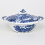 Johnson Brothers, Staffordshire - Inglaterra(Fundada em 1883). Belíssima terrina com tampa executada em faiança inglesa, padrão Watermill. Decoração monocromática em azul sob esmalte, representando paisagem rural com moinho hidráulico, executada por estampagem. A composição mostra edifício de moinho com roda dágua em funcionamento, pequeno dique e queda d'água, acompanhados por casas campestres, árvores frondosas, figuras humanas em ambiente bucólico e céu anuviado ao fundo; bojo de formato hemisférico, abas laterais integradas, orla e tampa modeladas com delicado movimento ondulado, borda recortada com arcos em repetição, puxador em forma de domo. Marca da manufatura no verso. Medidas: Alt.:  13 x Diam.: 25,5 cm
